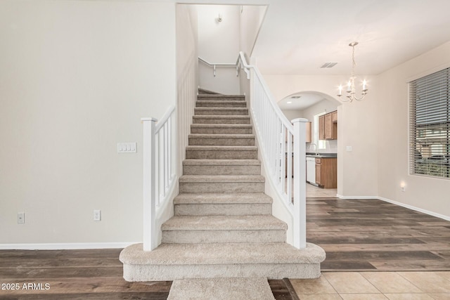 staircase featuring an inviting chandelier, hardwood / wood-style floors, and sink