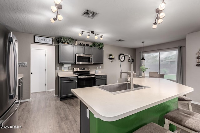 kitchen with stainless steel appliances, rail lighting, light countertops, light wood-type flooring, and baseboards