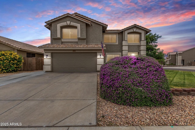 mediterranean / spanish home with stucco siding, driveway, a tile roof, and an attached garage