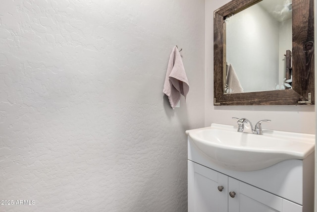 bathroom with a textured wall and vanity