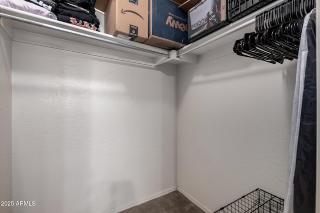walk in closet featuring dark colored carpet