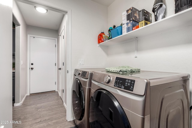 laundry room featuring independent washer and dryer, light wood-style flooring, and baseboards