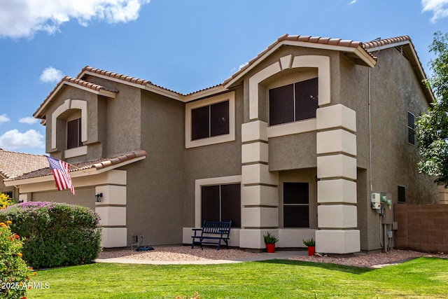rear view of house featuring a tiled roof, stucco siding, and a yard