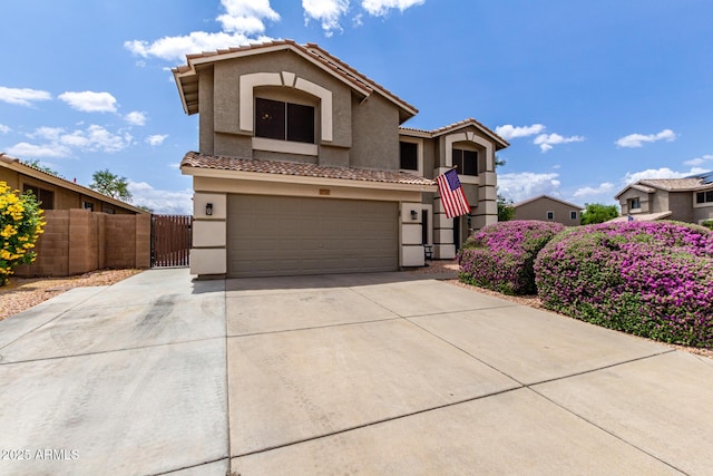 mediterranean / spanish house with stucco siding, a garage, a gate, a tiled roof, and concrete driveway