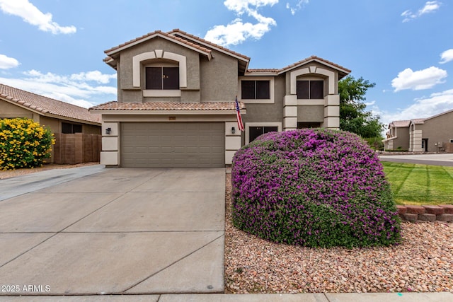 mediterranean / spanish house with stucco siding, an attached garage, concrete driveway, and a tile roof
