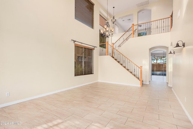 322 E Caribbean Dr, Casa Grande, AZ 85122 - unfurnished living room with arched walkways, stairs, a towering ceiling, a chandelier, and baseboards