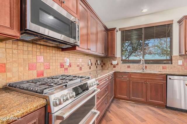 322 E Caribbean Dr, Casa Grande, AZ 85122 - kitchen with stainless steel appliances, a sink, backsplash, light stone countertops, and light wood-type flooring