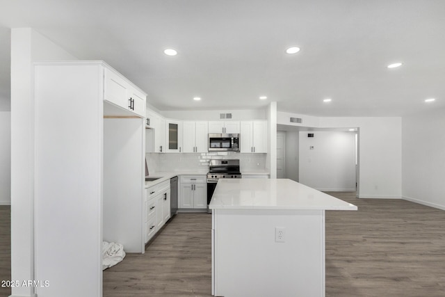 kitchen featuring tasteful backsplash, white cabinetry, a center island, stainless steel appliances, and light hardwood / wood-style flooring