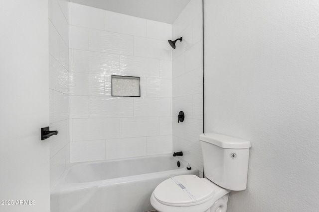 bathroom with tiled shower / bath combo and toilet