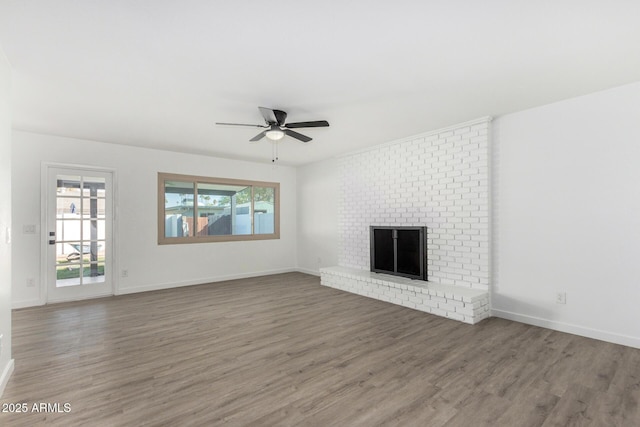 unfurnished living room featuring dark hardwood / wood-style flooring, a brick fireplace, and ceiling fan