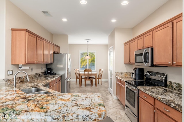 kitchen with light stone countertops, sink, hanging light fixtures, and appliances with stainless steel finishes