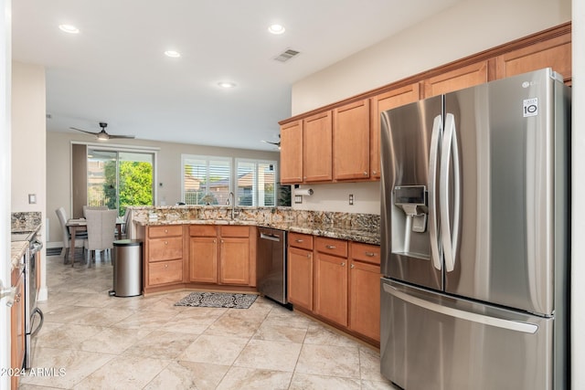 kitchen featuring ceiling fan, sink, kitchen peninsula, stone countertops, and appliances with stainless steel finishes