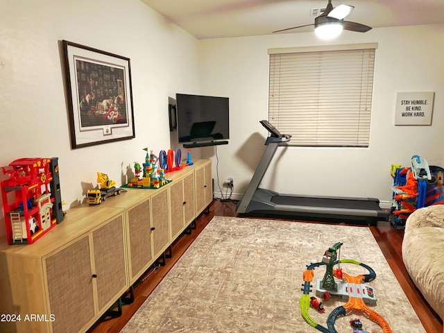 exercise room with ceiling fan and dark wood-type flooring