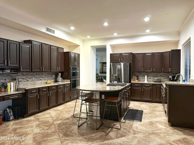 kitchen with a center island, stainless steel appliances, dark brown cabinetry, and a breakfast bar area