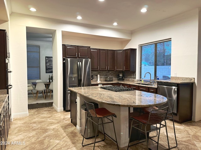 kitchen with light stone countertops, a breakfast bar, a kitchen island, and stainless steel appliances