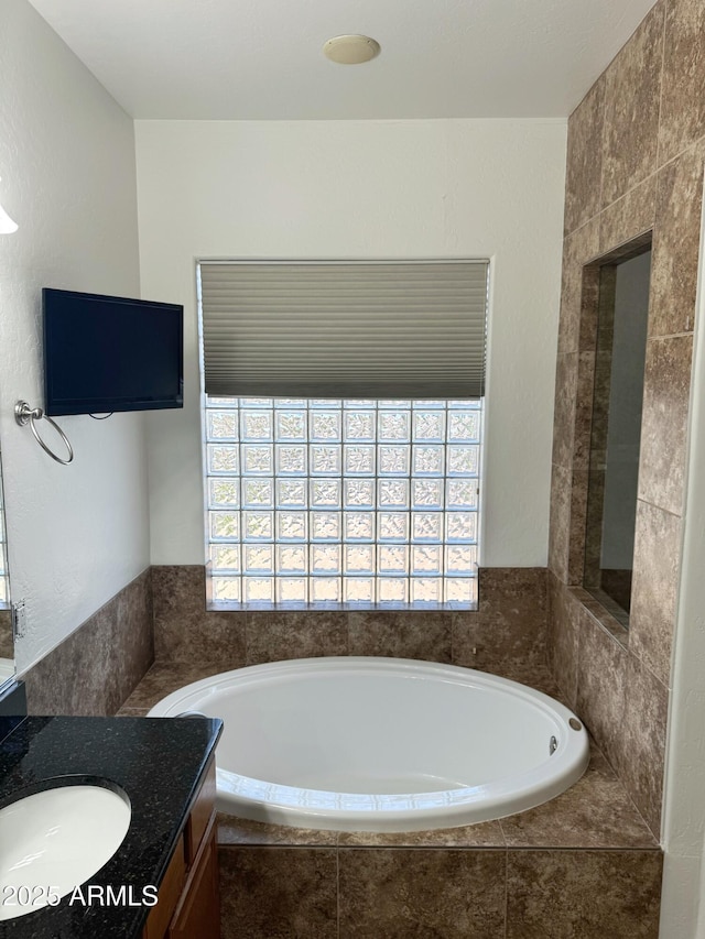 bathroom featuring tiled tub and vanity