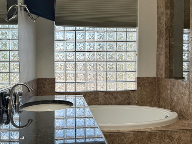 bathroom with sink and tiled tub