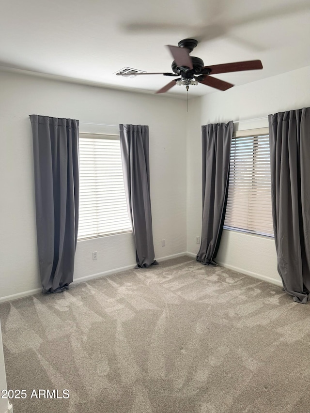 carpeted empty room with a wealth of natural light and ceiling fan