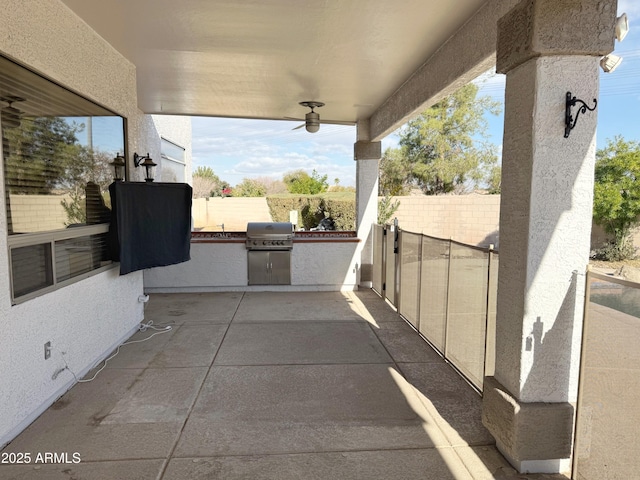 view of patio with area for grilling, ceiling fan, and exterior kitchen