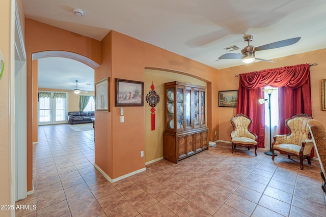 living area featuring visible vents, arched walkways, baseboards, and light tile patterned flooring