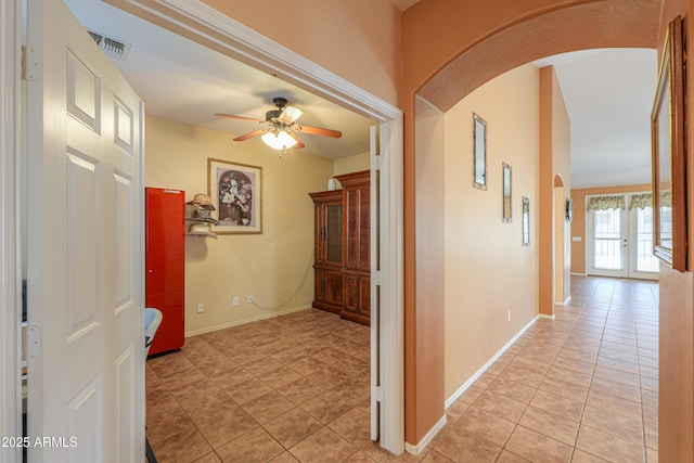 corridor with arched walkways, visible vents, baseboards, and light tile patterned flooring