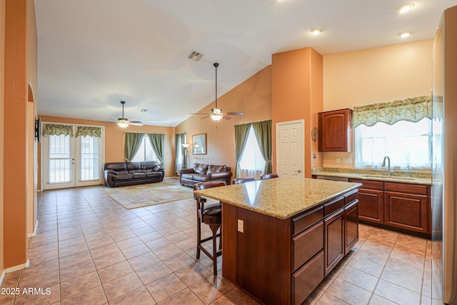 kitchen with light tile patterned floors, visible vents, a sink, and a center island