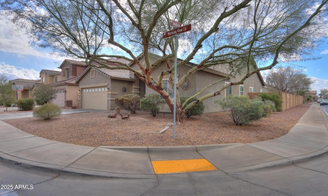 view of front of house featuring fence, driveway, a tiled roof, and stucco siding