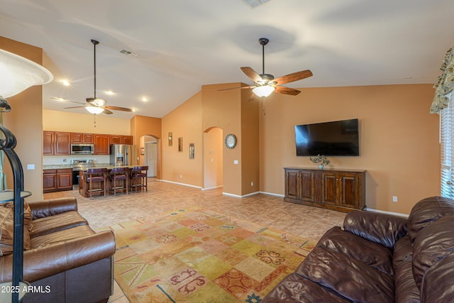 living area with arched walkways, ceiling fan, visible vents, baseboards, and vaulted ceiling