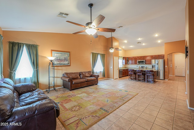 living room featuring arched walkways, light tile patterned floors, lofted ceiling, visible vents, and baseboards
