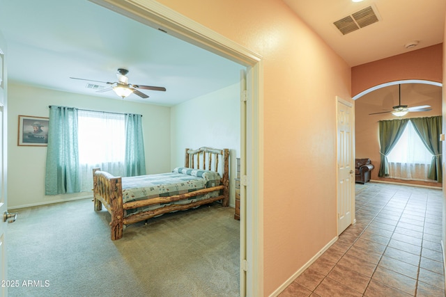 carpeted bedroom featuring ceiling fan, tile patterned flooring, visible vents, and baseboards