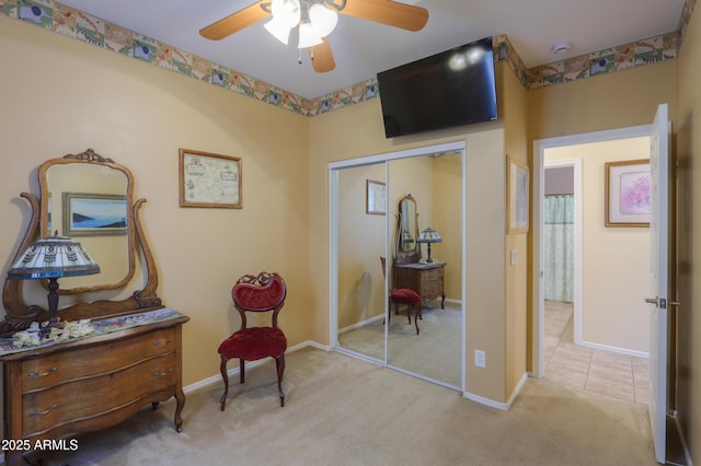 living area featuring light carpet, baseboards, and a ceiling fan