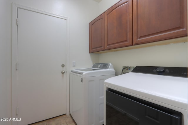 washroom featuring light tile patterned flooring, washing machine and clothes dryer, and cabinet space