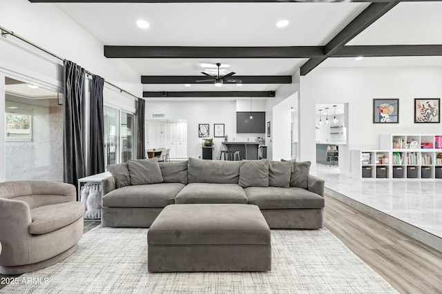 living room featuring ceiling fan, hardwood / wood-style floors, and beamed ceiling