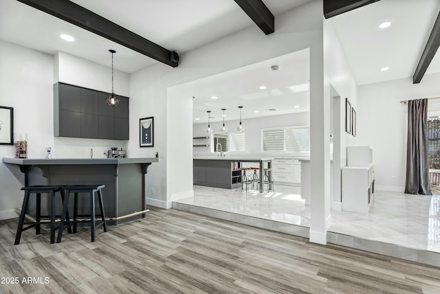 kitchen with kitchen peninsula, beamed ceiling, a breakfast bar area, and pendant lighting