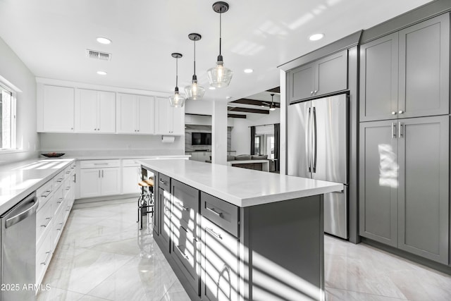 kitchen featuring pendant lighting, a center island, stainless steel appliances, beamed ceiling, and gray cabinetry