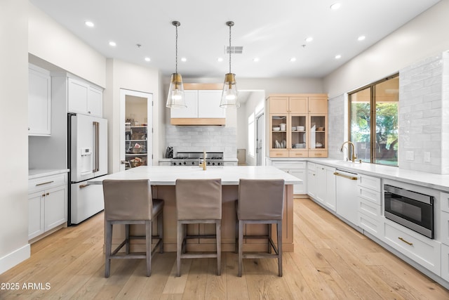 kitchen with tasteful backsplash, a kitchen island with sink, white appliances, and white cabinetry