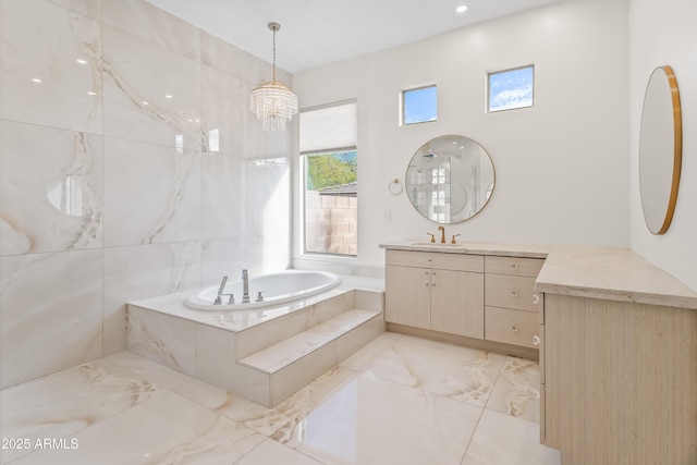 bathroom featuring vanity, an inviting chandelier, and tiled tub