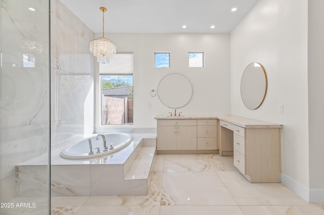 bathroom featuring vanity, a notable chandelier, and a relaxing tiled tub