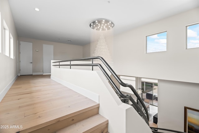 staircase with wood-type flooring and a chandelier