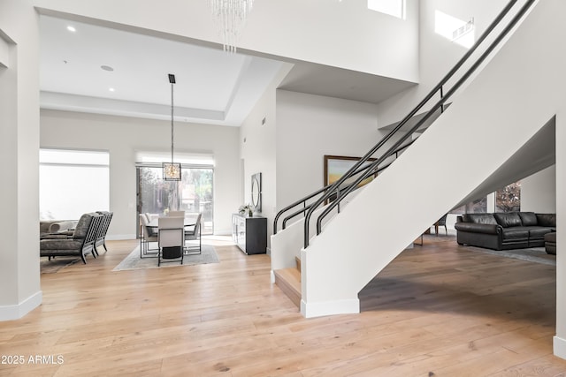 entrance foyer featuring light wood-type flooring, an inviting chandelier, and a high ceiling