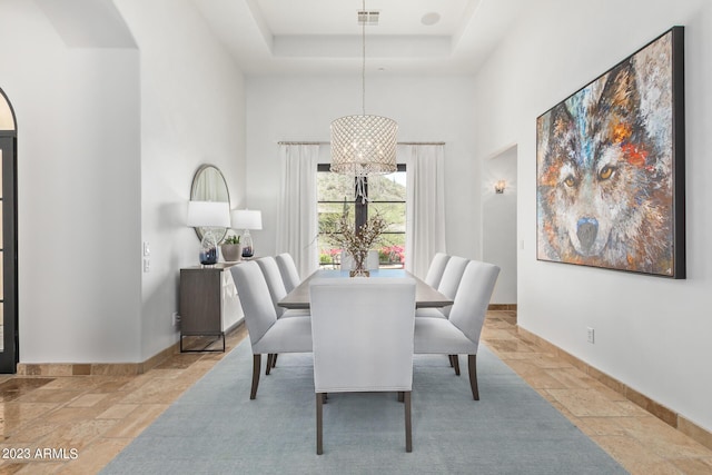 dining room featuring a chandelier, a towering ceiling, and a tray ceiling