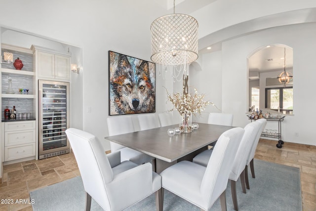 dining area featuring wine cooler and an inviting chandelier