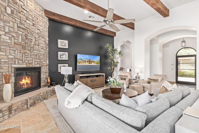 living room featuring beam ceiling, ceiling fan, and a fireplace