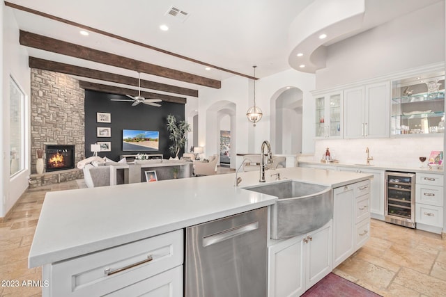 kitchen with white cabinets, beam ceiling, a fireplace, and wine cooler