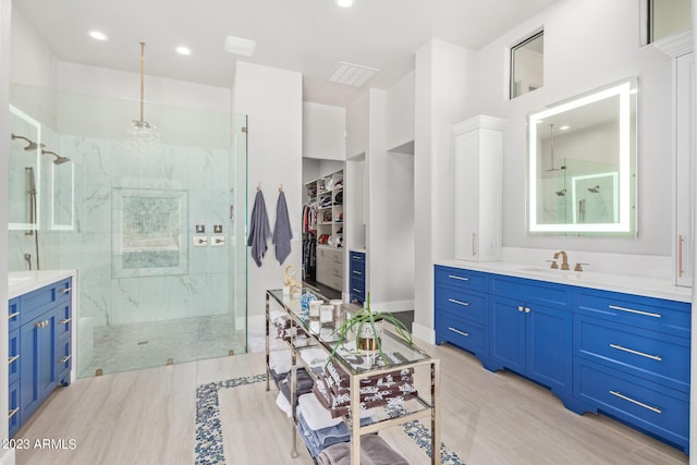 bathroom with a tile shower and vanity