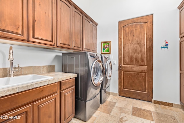 clothes washing area with cabinets, washer and clothes dryer, and sink