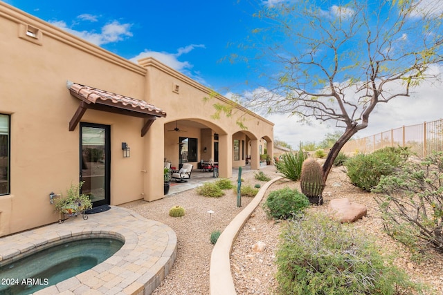 back of house with an in ground hot tub and a patio