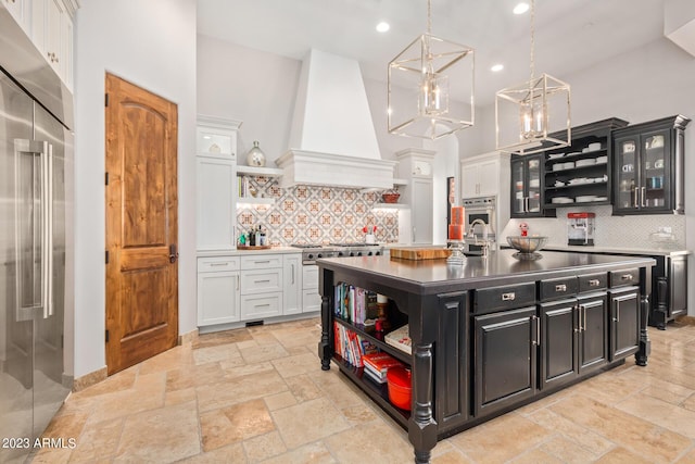 kitchen featuring a center island with sink, custom exhaust hood, white cabinetry, and appliances with stainless steel finishes