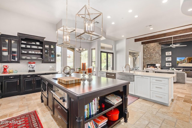 kitchen featuring sink, white cabinets, hanging light fixtures, and a kitchen island