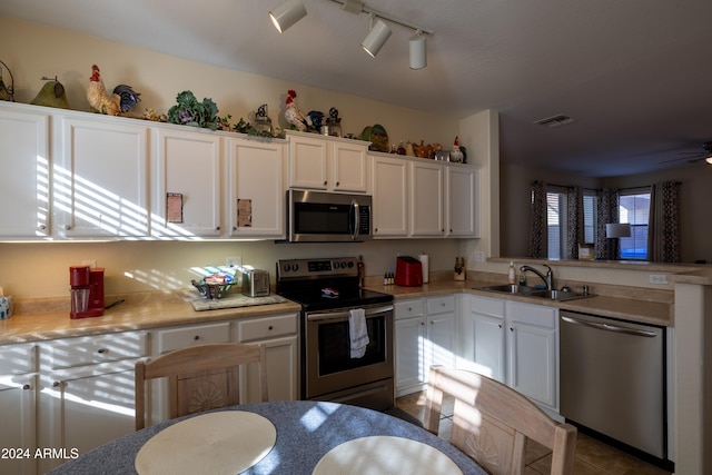 kitchen featuring track lighting, sink, ceiling fan, white cabinetry, and stainless steel appliances